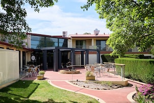 Un patio con mobiliario exterior, una chimenea y un edificio con acceso de vidrio.