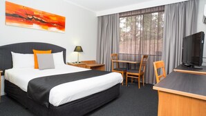 A hotel room with a bed, desk, chairs, a television, and a painting on the wall. - Alpha Hotel Canberra (Canberra)