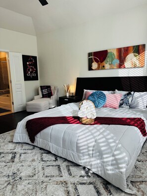 A bedroom with a large bed, a nightstand, a lamp, and a wall art piece.