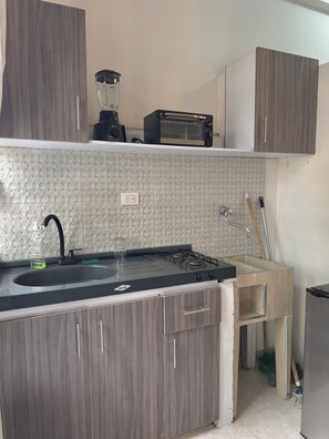 Una cocina con estufa a gas, un fregadero, un tostador y una licuadora sobre la encimera.