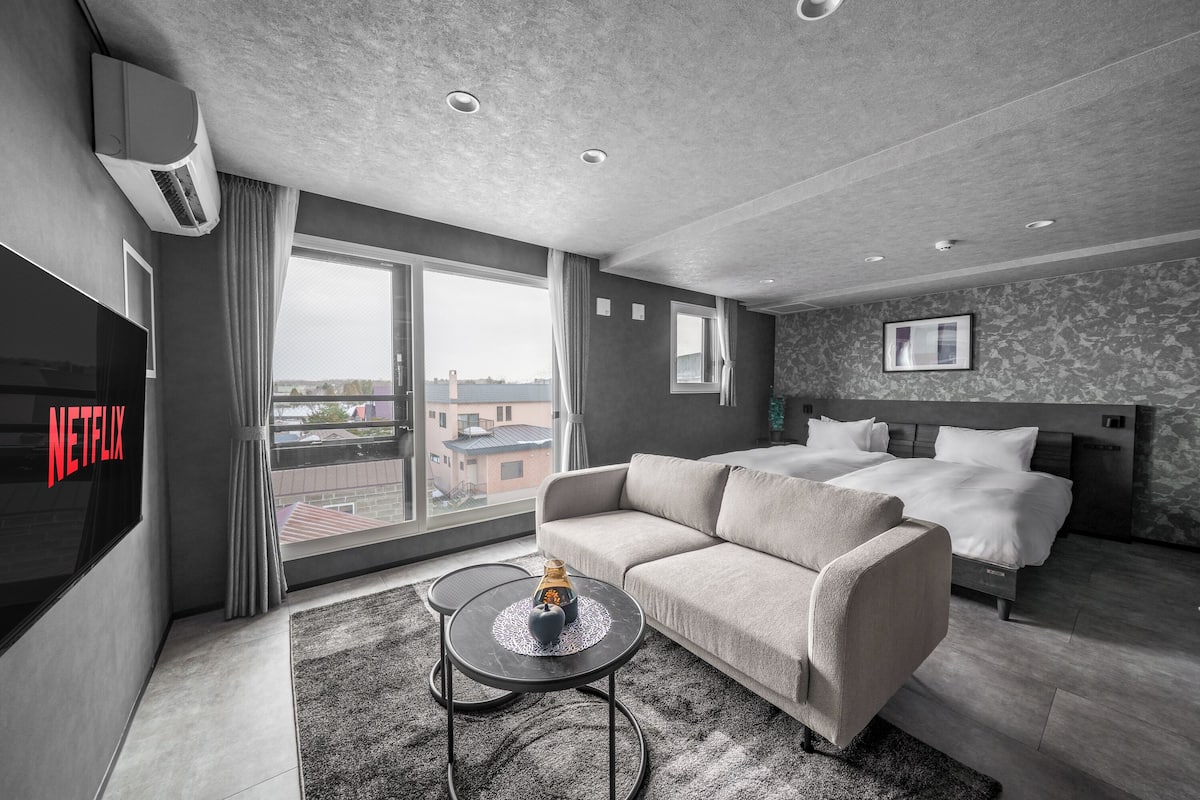 Ein modernes Hotelzimmer mit einem großen Bett, einer Sitzecke, einem Fernseher und Blick auf die Stadt.