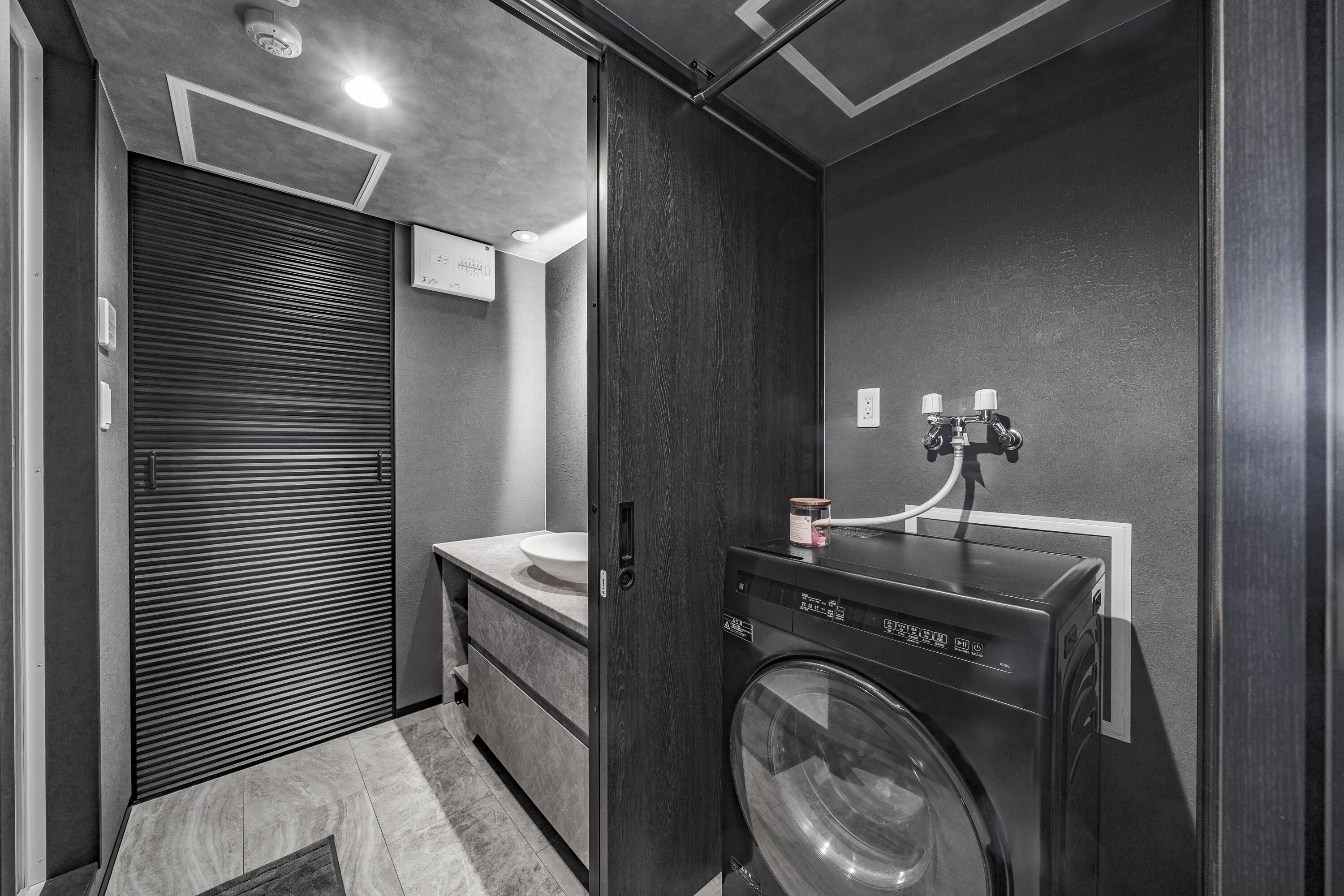 A compact, modern bathroom with a built-in washing machine, a sink, and a towel rack.