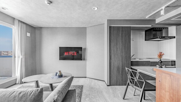A modern living room with a sofa, a coffee table, and a TV displaying 'NETFLIX'. - GRAN HILLS (Chitose)