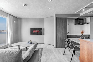 A modern living room with a sofa, a coffee table, and a TV displaying 'NETFLIX'. - GRAN HILLS (Chitose)
