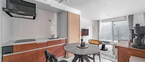 A modern kitchen with a built-in oven, a dining area with a round table, and a large window providing natural light.