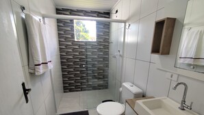 Ein Badezimmer mit Dusche, Toilette, Waschbecken und einem Handtuchhalter.