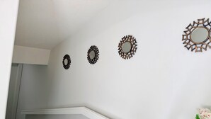 Eine Treppe mit weißer Handlauf, eine Wand mit drei dekorativen Spiegeln und eine Vase mit Blumen.