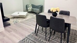 Ein modernes Wohnzimmer mit Essbereich, einer Couch, einem Couchtisch und einem Bild an der Wand.