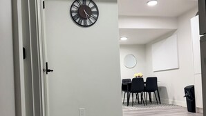 Ein modernes Interieur mit Essbereich, einer Wanduhr und einem hellen Boden.