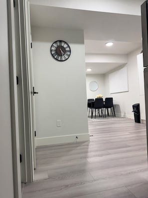 A modern interior with a dining area, a wall clock, and a light-colored floor.