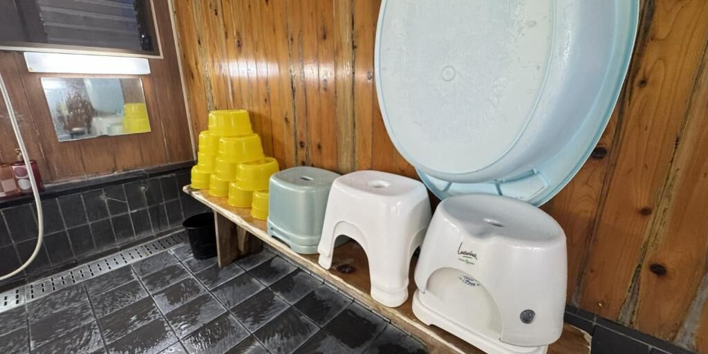 A restroom with a wooden wall, a tiled floor, and a shelf with yellow and white dispensers.