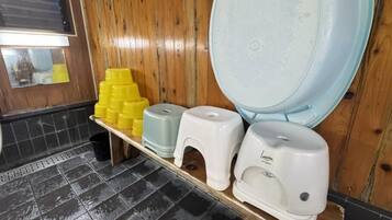 A restroom with a wooden wall, a tiled floor, and a shelf with yellow and white dispensers.