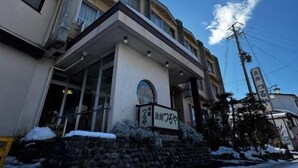 A hotel with a stone facade, a sign with Japanese characters, and a clear blue sky. - turuyaryokan (Yamanouchi)