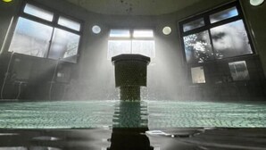 A swimming pool with a central column, large windows, and a ceiling with visible wear. - turuyaryokan (Yamanouchi)