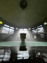 A swimming pool with a central column, large windows, and a ceiling with visible wear.