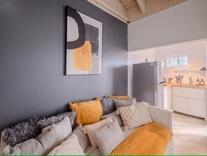 A modern living room with a sofa, cushions, and a large abstract painting on the wall. - Zoloto Penthouse Studio (Montego Bay)