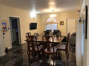 A dining area with a marble floor, a chandelier, and a flat-screen TV mounted on the wall. - Sky Castle penthouse, 3bdr (Ocho Rios)
