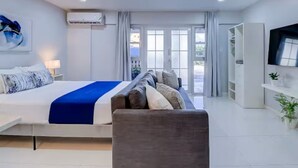 Ein modernes Hotelzimmer mit Bett, einer Sitzecke, einem Fernseher und einem Kleiderschrank.