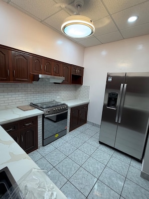 A kitchen with a stove, oven, refrigerator, and wooden cabinets.