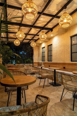 An outdoor seating area with wicker furniture and hanging wicker lamps. - Bruma Verde Casa Hotel (Medellín)
