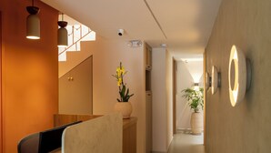 Un moderno vestíbulo de hotel con una recepción, una escalera y una planta en maceta.