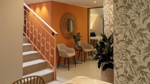 Un comedor con una mesa, sillas y una escalera que sube a otra habitación.