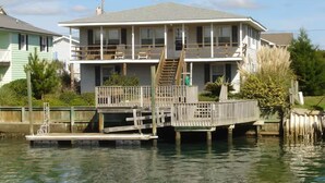 Une maison à deux étages avec une jetée qui s’avance dans l’eau.