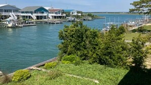 Un port de plaisance avec des bateaux amarrés, un bâtiment doté d’un toit en pente et une zone herbeuse avec des arbres.