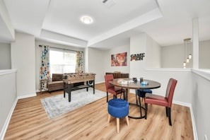 A spacious living area with a foosball table, a round dining table with chairs, and a sofa.