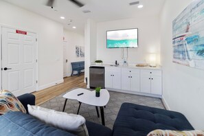 Ein modernes Wohnzimmer mit einer Couch, einem Couchtisch und einem an der Wand befestigten Fernseher.