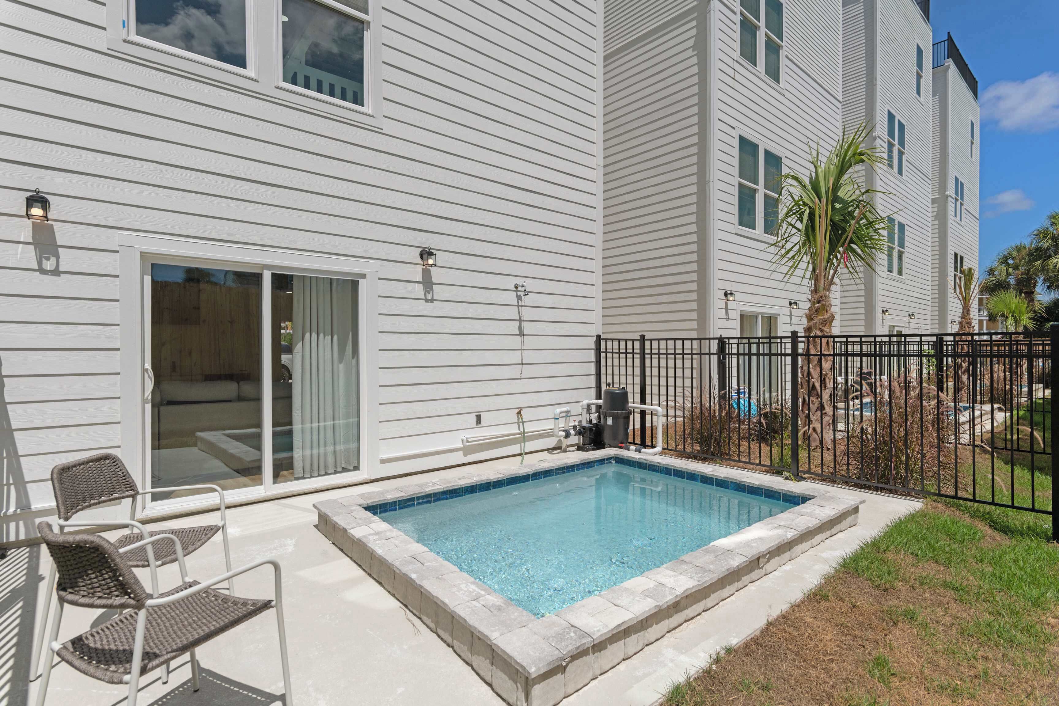 A residential building with a swimming pool, sliding glass doors, and a fenced patio area.