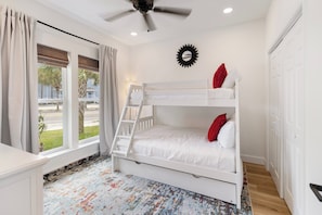 A bedroom with a bunk bed, a ceiling fan, a window with curtains, and a patterned rug. - Villas at Laguna Beach #10 - Gulf Views, Pool, Rooftop Terrace, Pets OK! (Panama City Beach)