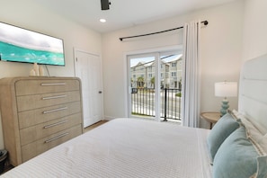 A hotel room with a bed, a dresser, a television, and a view of the outside. - Villas at Laguna Beach #10 - Gulf Views, Pool, Rooftop Terrace, Pets OK! (Panama City Beach)