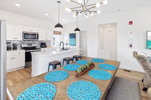 A modern kitchen with white cabinets, a built-in microwave, and a central island with stools. - Villas at Laguna Beach #10 - Gulf Views, Pool, Rooftop Terrace, Pets OK! (Panama City Beach)