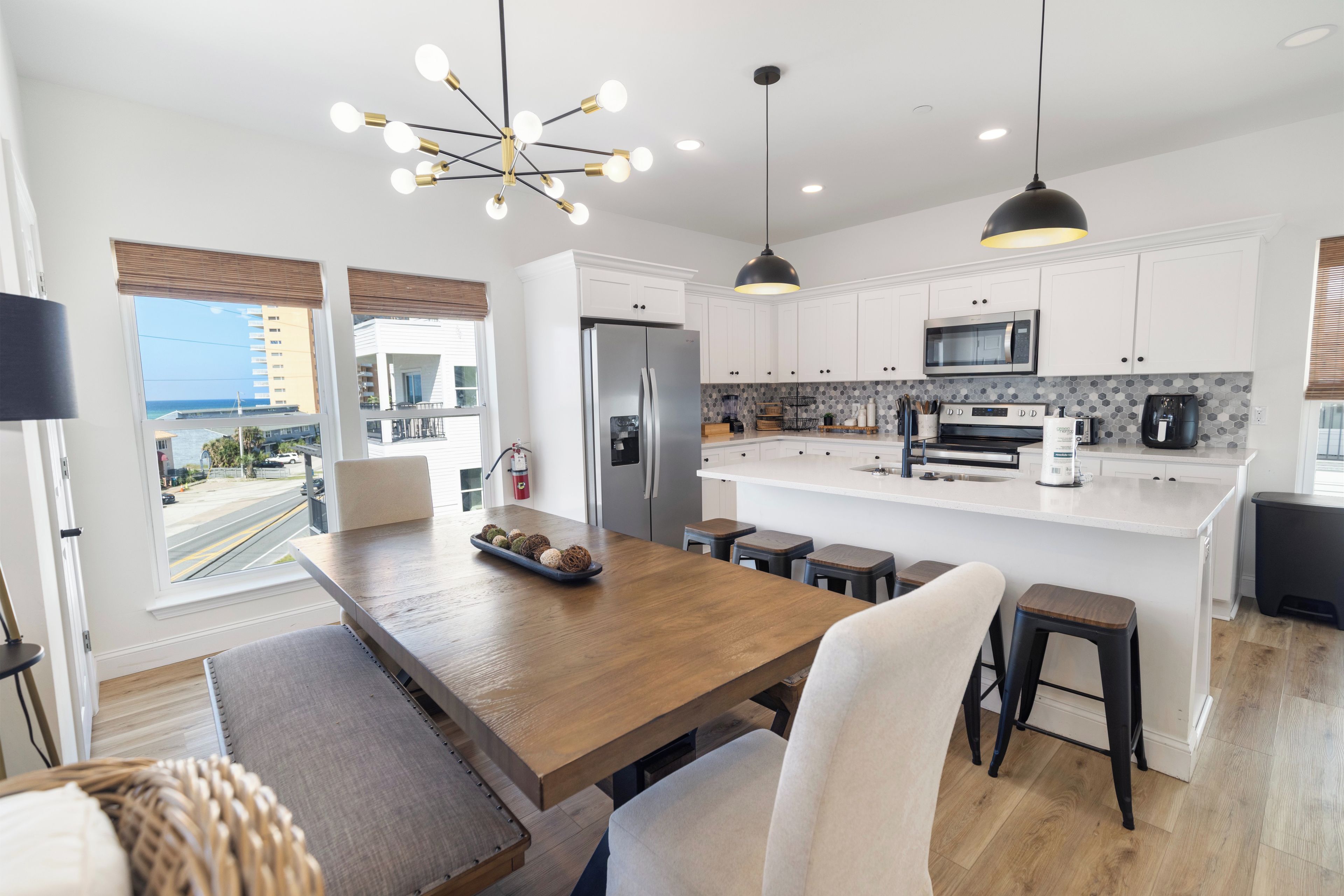 A modern kitchen with a central island, white cabinetry, stainless steel appliances, and a view of the ocean.