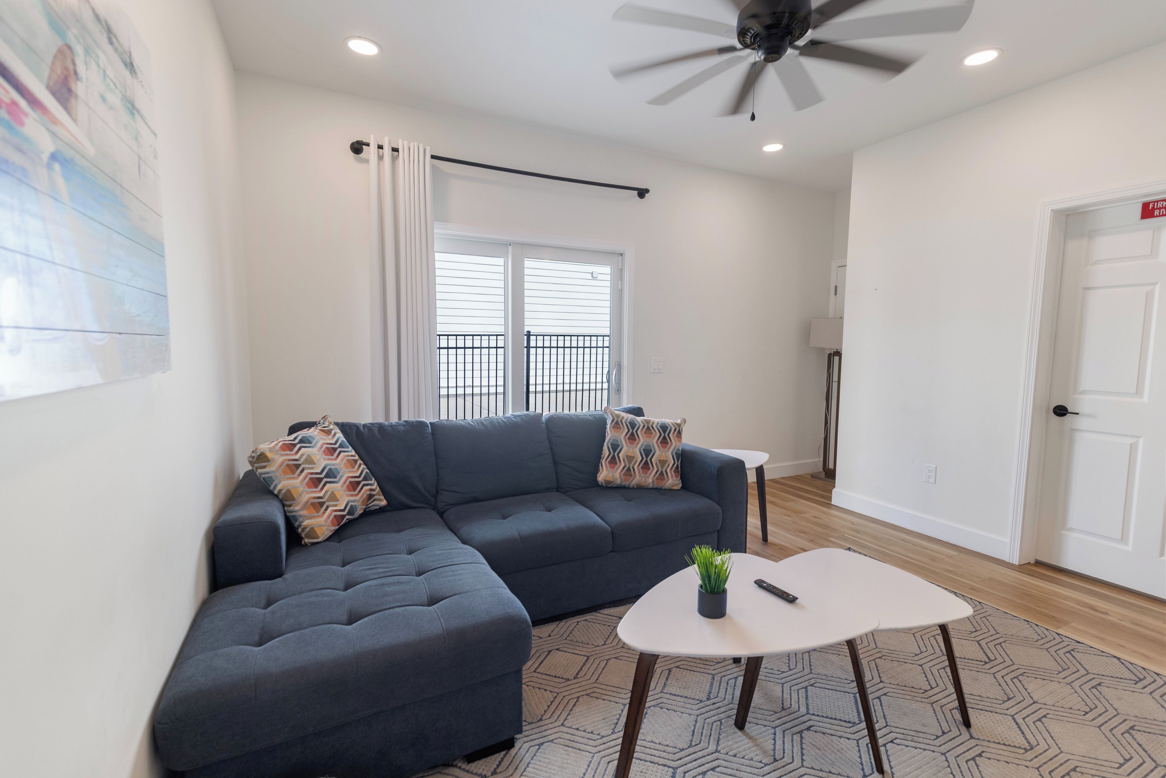 A modern living room with a sectional sofa, a small white table, and a ceiling fan.
