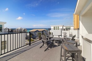Ein Balkon mit Gartenmöbeln, Blick auf den Ozean und angrenzende Gebäude.