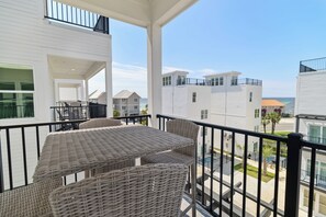 A balcony with wicker furniture and a view of neighboring buildings. - 🌊 Villas Laguna Beach #5 - Pool, Rooftop Terrace, Pets OK!, Walk to Beach (Panama City Beach)