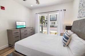A bedroom with a bed, a TV on a dresser, a window with curtains, and a view of the outside. - Villas of Laguna Beach #7 - Gulf Views. Pets Ok! Rooftop Terrace. Walk to Beach (Panama City Beach)