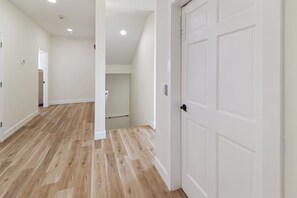 A spacious hallway with wooden flooring, white walls, and a white door. - Villas of Laguna Beach #7 - Gulf Views. Pets Ok! Rooftop Terrace. Walk to Beach (Panama City Beach)