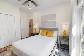 A bedroom with a bed, two nightstands, a ceiling fan, and a window. - 🌊 Villas Laguna #8 - Beach Retreat, Pool, Rooftop Terrace, Pets! (Panama City Beach)
