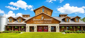 A winery with a prominent wooden facade, a stone base, and a red entrance door. - 🌊 Villas Laguna #8 - Beach Retreat, Pool, Rooftop Terrace, Pets! (Panama City Beach)