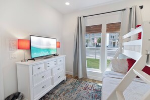 A hotel room with a television on a white dresser, a patterned rug, and a view of the street through a large window. - 🌊 Villas Laguna Beach #9 - Gulf Views, Rooftop Terrace, Private Pool, Pets! (Panama City Beach)