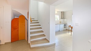 Eine Treppe führt zu einem Küchenbereich mit weißen Schränken und einem Geschirrspüler.