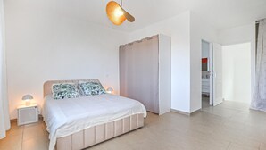 Ein Schlafzimmer mit Bett, Nachttischlampen, einem Kleiderschrank und einem durchgegangenen Tür sichtbaren Badezimmer.