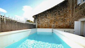 En swimmingpool med en mur av sten och en metallstege.
