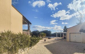 Ein Gebäude mit überdachter Terrasse, Kiesgrund und blauem Himmel.
