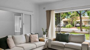 Ein Wohnzimmer mit zwei Sofas, einem Couchtisch und Blick auf die Straße.