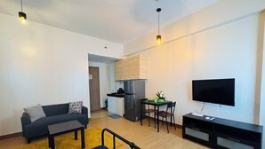 Un appartement moderne comprenant un canapé, une table à manger, un coin cuisine et un téléviseur.