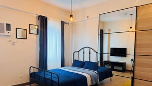 Une chambre à coucher avec un lit, une télévision, un miroir et un plancher en bois.
